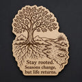 Front close-up of Tree Wood Plaque Stay Rooted Quote Sign Inspirational Birch Wall Art With Stream and Roots, showing dark engraving on natural birch wood.