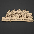 Front close-up of Olive Branch Wood Plaque Seek Peace Quote Sign Long Birch Wall Art With Natural Branch, showing dark engraving on natural birch wood.