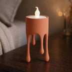 Terracotta HoverDrip flameless tealight holder glowing on a bedside table