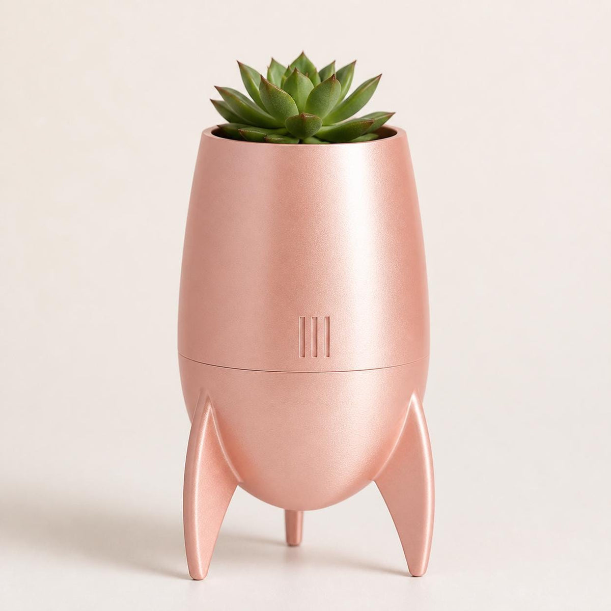 Close-up low-angle view of the NovaPod planter in Silk Rose Gold with a succulent