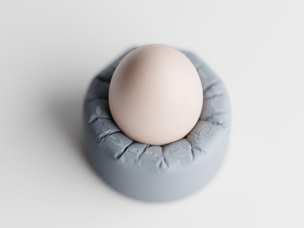 High-angle close-up of the PillowNest egg cup and rounded cushion-look rim