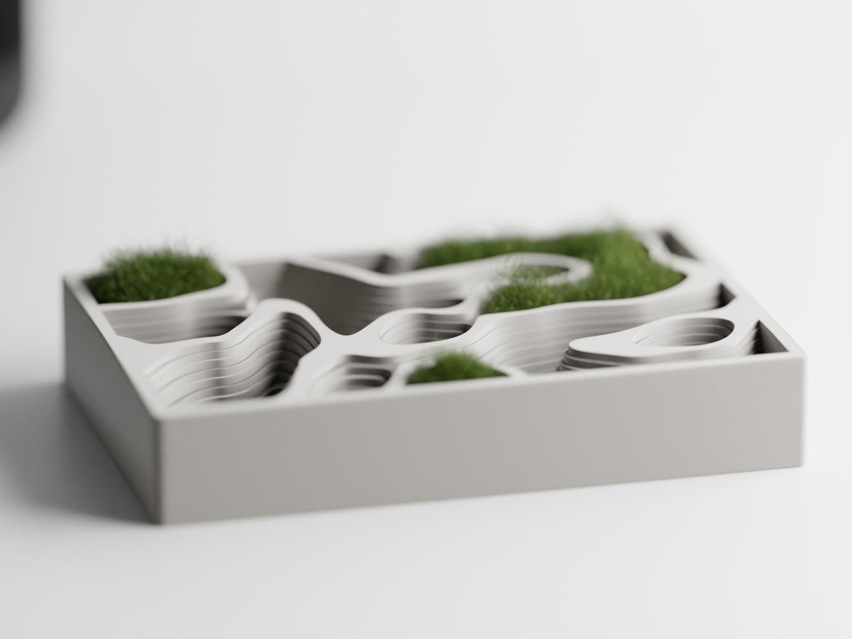 Front view of the ContourCove topographic tray styled with small patches of dry moss