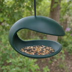 Forest Green Mooncurve Haven crescent hanging bird feeder in a leafy garden