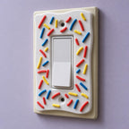 Angled close-up of the Decora rocker SprinkleCrust plate and its raised frosting and sprinkles