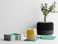 Close-up of the complete CanopyLace square coaster set with holder beside a hot drink