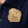 Friendly Wave Kind Hello engraved birch reward badge shown close up in a realistic meeting setting.