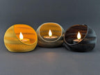 Three TideNest ripple holders in yellow gray and charcoal with warm LED tea lights