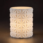 Close-up of the PrismGlow geometric LED tealight sleeve in White with a warm internal glow