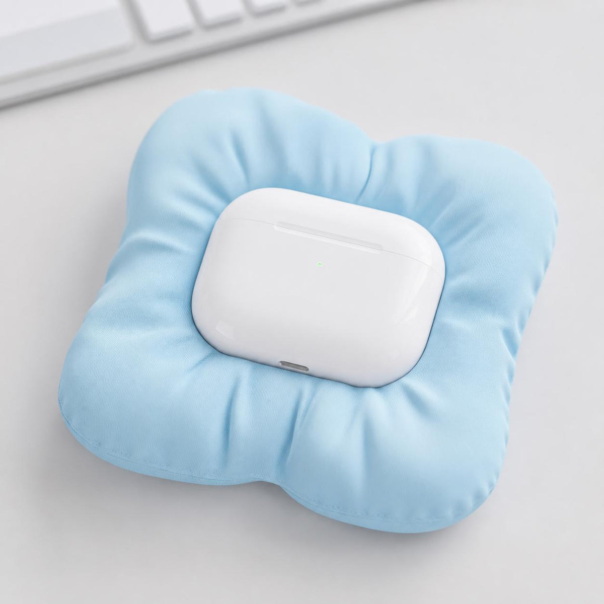 Close-up of the PuffNest earbud case dock in Ice Blue holding a plain white charging case