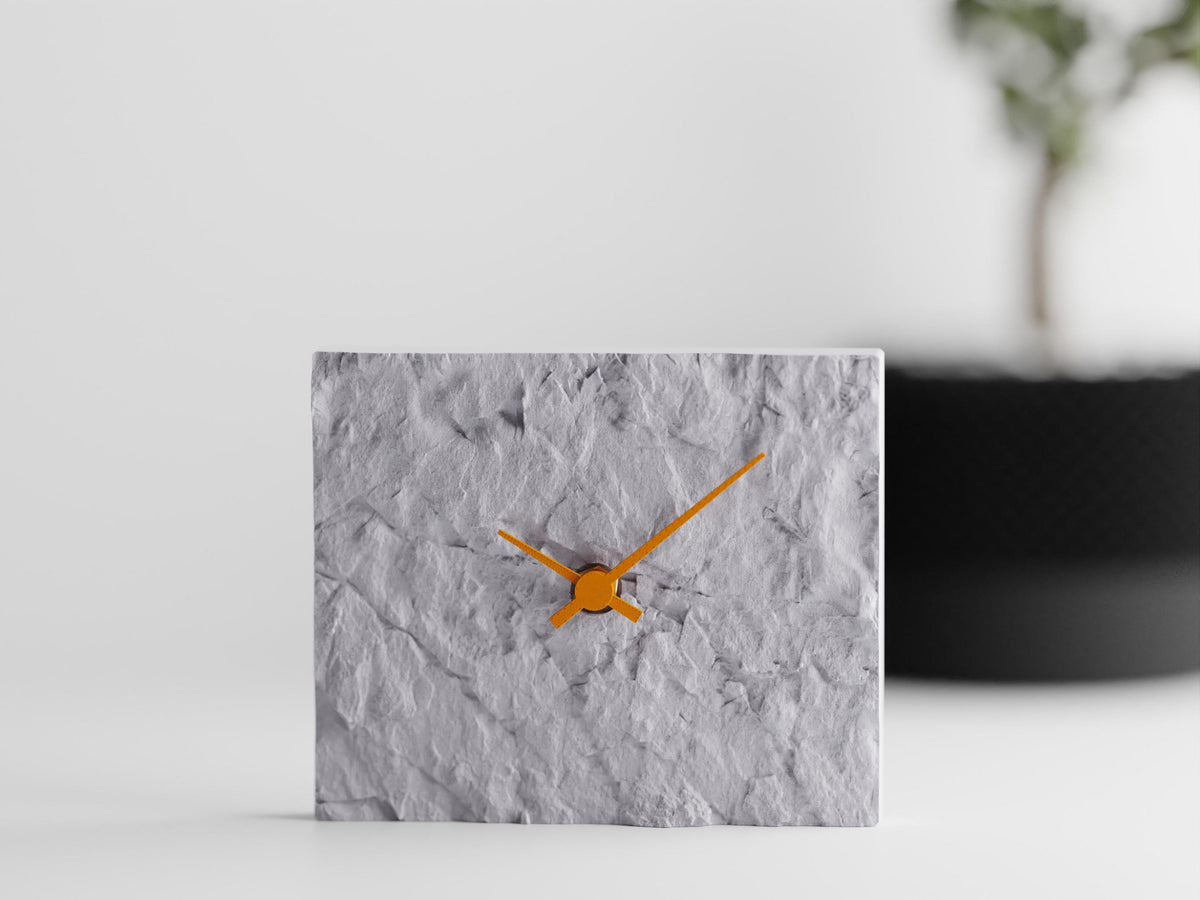 Stonewake sculptural table clock in White Marble with Orange hands on a modern shelf