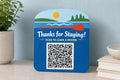 PaddleBright multicolor lake guest review sign upright on a waterfront rental console with a finished sample QR code.