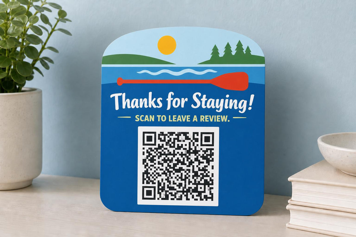 PaddleBright multicolor lake guest review sign upright on a waterfront rental console with a finished sample QR code.