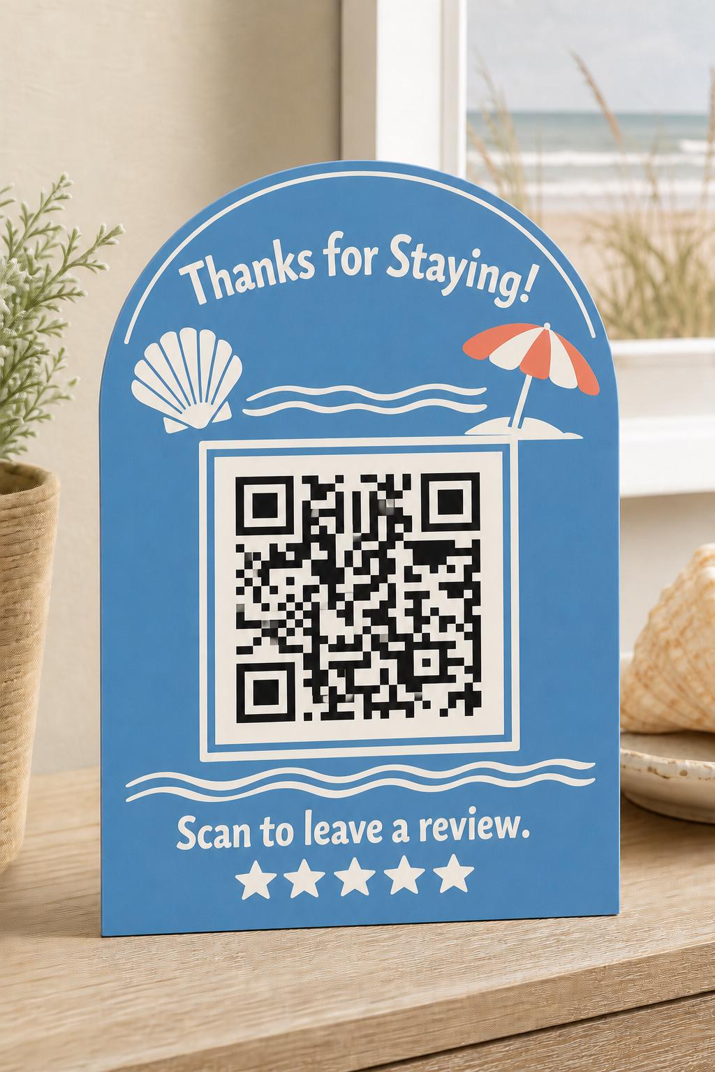 ShoreShell multicolor coastal guest review sign upright on a beach-rental console with a finished sample QR code.