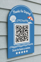 ShoreShell multicolor coastal review sign mounted on a pale blue wall from a close side angle with a finished sample QR code.