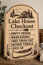 Pinewater engraved birch lake house checkout sign upright on a rustic entry console in a close-up view.