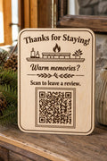 Fireside Keepsake engraved birch review sign upright on a cozy cabin console with a finished sample QR code.