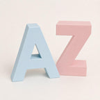 Close-up of closed Sky Blue A and Sakura Pink Z letter-shaped keepsake boxes on a warm white background