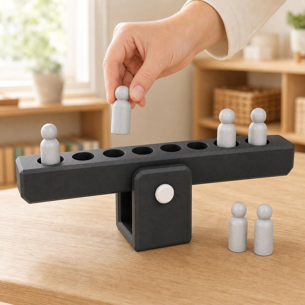 Adult hand placing a gray peg weight into the charcoal BalanceBridge activity on a wood learning table.