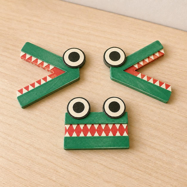 Complete ChompCompare set with green greater-than, less-than, and equal crocodile symbols arranged on a pale wood table.