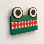 Green equal-sign ChompCompare crocodile with two eyes and opposing white teeth viewed close-up on a blank whiteboard.