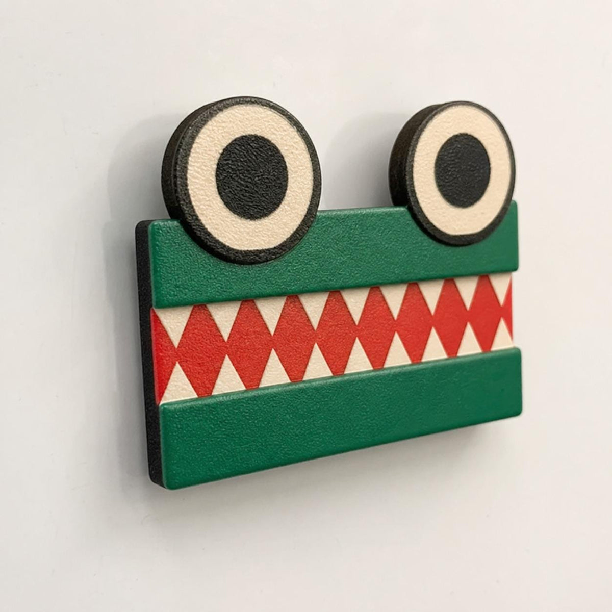 Green equal-sign ChompCompare crocodile with two eyes and opposing white teeth viewed close-up on a blank whiteboard.