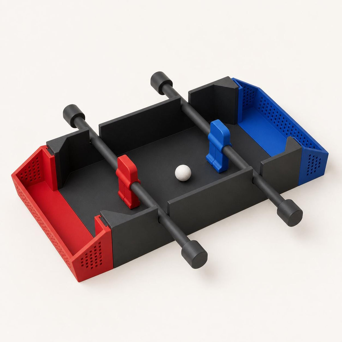 Close three-quarter view of the fully assembled KickArc tabletop soccer game in Charcoal, Scarlet Red, and Marine Blue on warm white