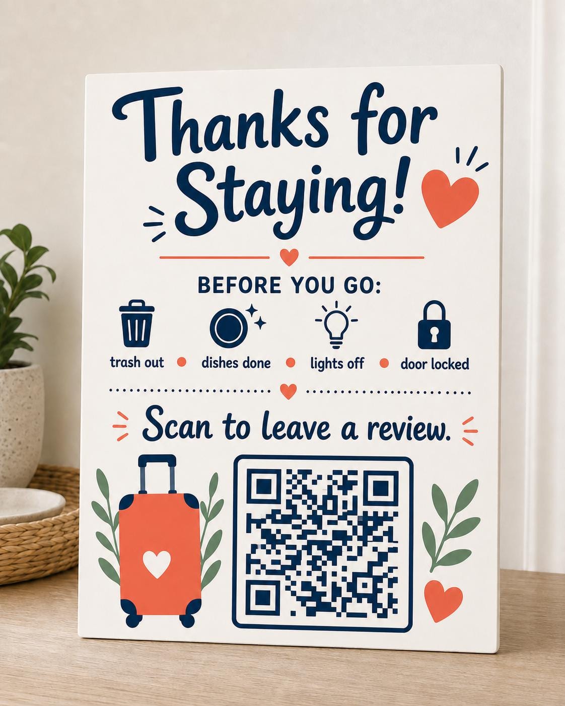 CoralKey navy and coral review sign upright on a vacation-rental entry console, shown close up with a finished sample QR code.