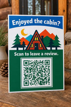 A-Frame Haven multicolor cabin guest review sign upright on a mountain-rental console with a finished sample QR code.