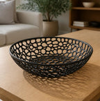 Cellarbor centerpiece bowl in black, three-quarter close-up on a white kitchen counter holding whole fruit.