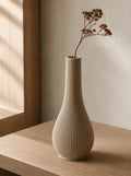 QuietStem Bud Vase in warm tan holding one dried blossom on a softly styled bedside table.