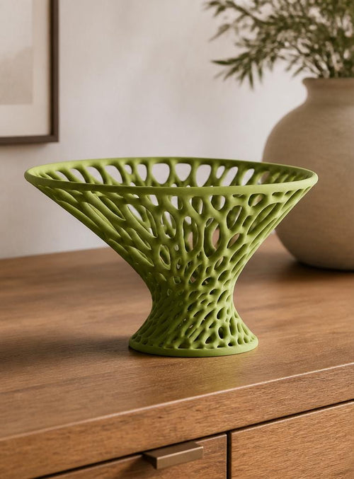 Airbloom pedestal bowl in dark green, straight-on close-up on a warm dining table showing its flared rim.