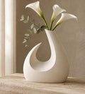 MoonGate Statement Vase in ivory holding dried stems on a warm entryway console with its crescent opening visible.