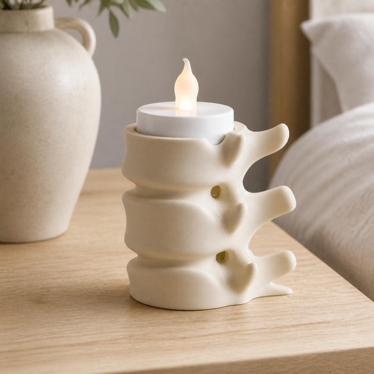 Beige compact SpineGlow flameless tealight holder on a minimalist bedside table