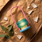 Elevated diagonal view of the complete Coral Cove lantern on kraft paper, showing its ribbed teal shade and pink arch.