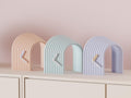 Arcspan Sculptural Desk Clock examples in contrasting colors on a pale cabinet, showing the finished clock faces and hands.