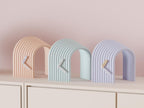 Arcspan Sculptural Desk Clock examples in contrasting colors on a pale cabinet, showing the finished clock faces and hands.