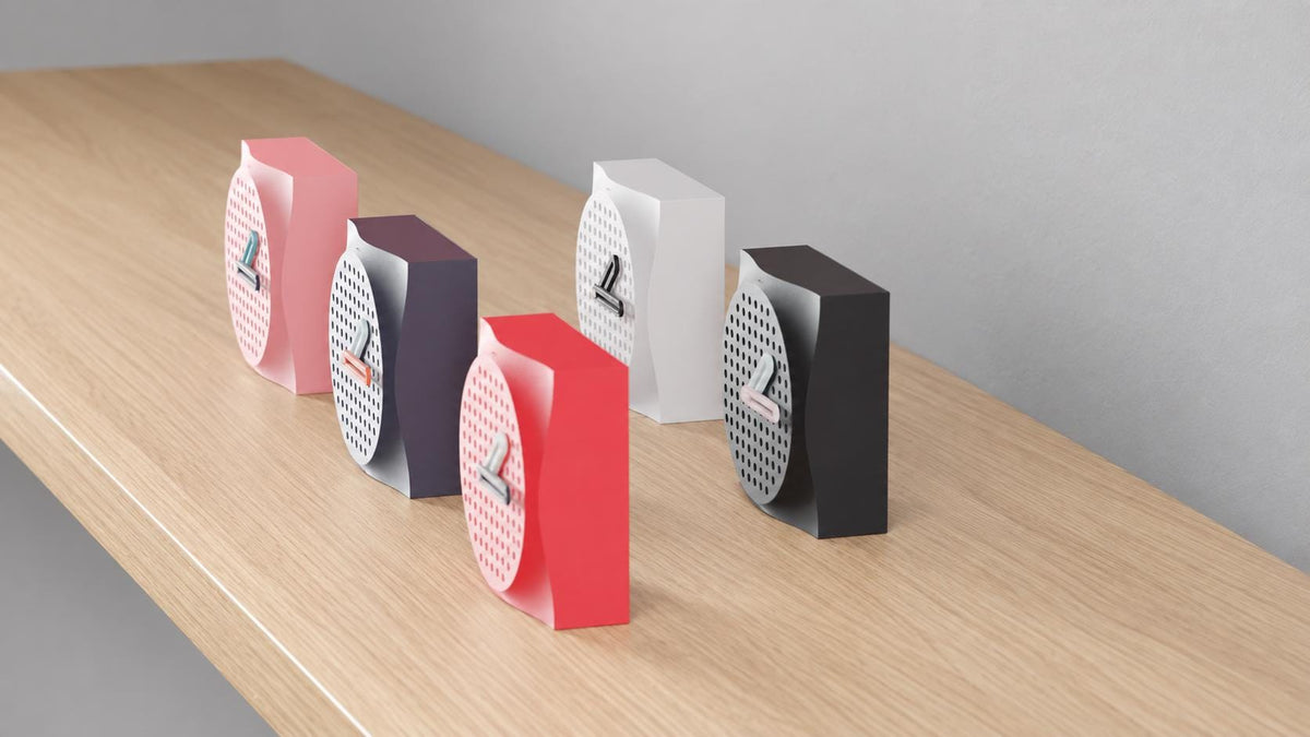 Alternate close-up of Dappledial Perforated Desk Clock examples on light oak, showing their colored faces, hands and body profiles.