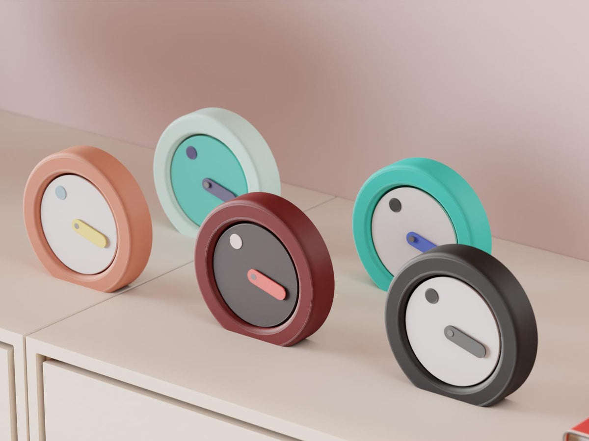 Orbitmark Moving Face Clock examples in contrasting colors on a pale cabinet, showing the finished clock faces and hands.