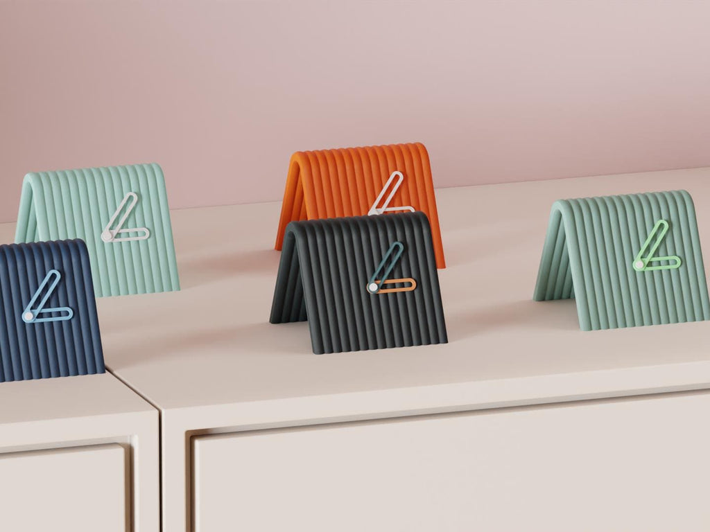 Linefold Compact Desk Clock examples in contrasting colors on a pale cabinet, showing the finished clock faces and hands.