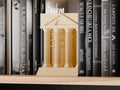Solstice Colonnade Book Nook in a light neutral color, shown from the front between books on a wooden shelf.