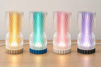 Four illuminated Rillora lamps with clear rippled outer shades, left to right: Amber Sand, Lagoon Mist, Blush Pearl and Lavender Night.