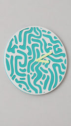 Flowmaze Wall Clock, turquoise and white organic pattern with yellow hands, alternate source-referenced close-up on a gray wall.