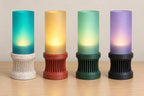 Four cordless Alvara lamps, left to right: Marble Tide, Granite Amber, Meadow Mist and Twilight Lilac, on a wood tabletop.