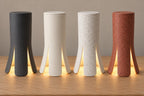 Four Lunareth lamps in Charcoal, Bone White, White Marble and Red Granite, each with a matching top and warm light beneath its flared feet.