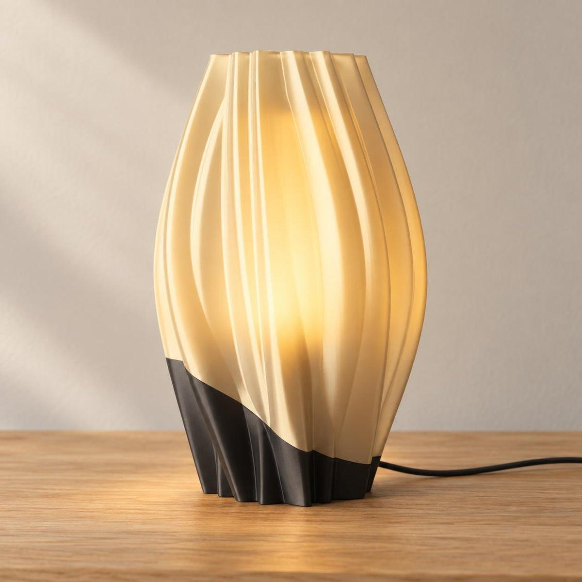Midnight Amber Orelune lamp with a Charcoal base and softly glowing Mellow Yellow diffuser and flowing outer shade, USB cord visible on an oak tabletop.