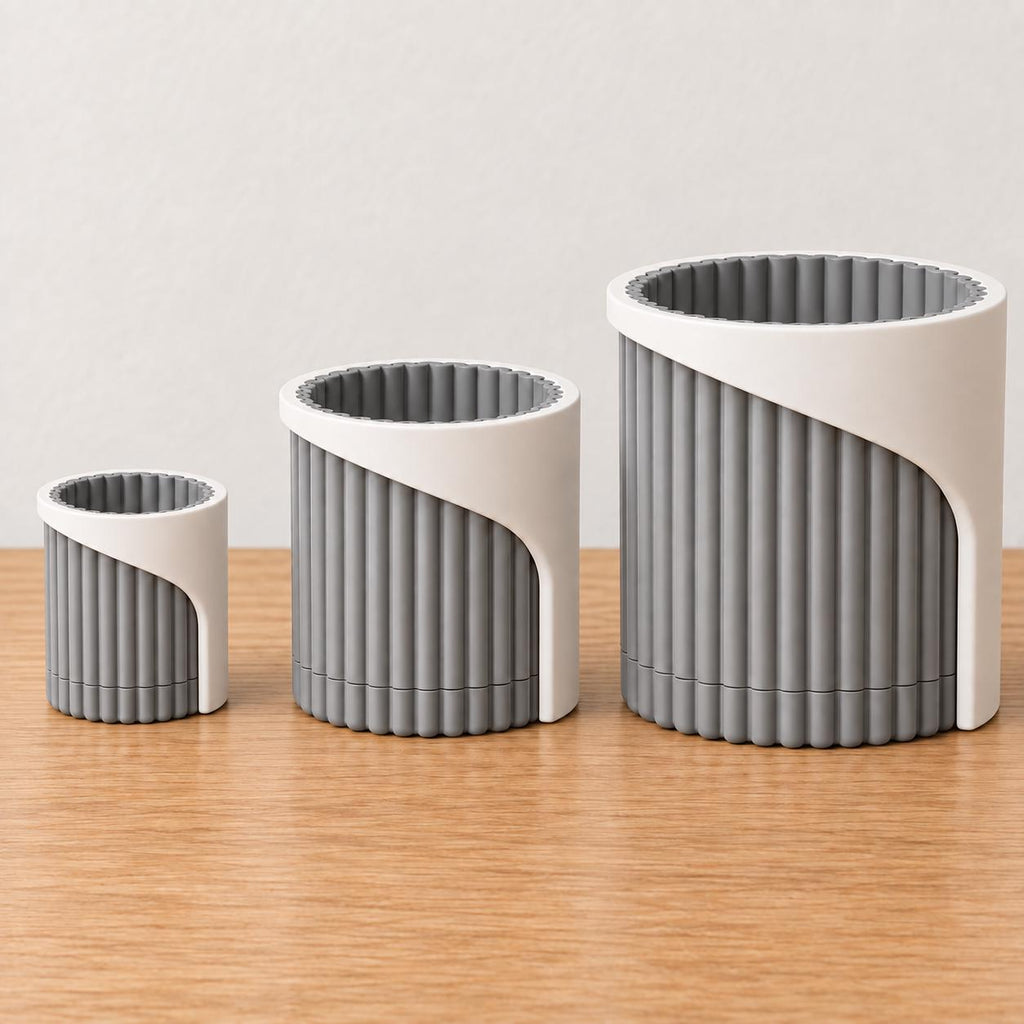 Three Linen Shadow Arvenna planters arranged from small to large on oak, showing proportional widths and the sweeping wrap over each ribbed pot.