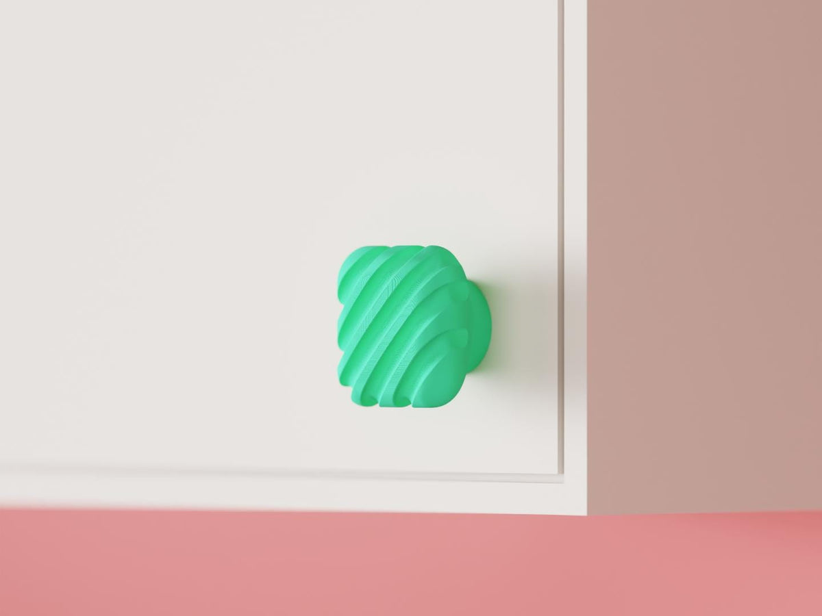 Green ribbed cabinet knob on a white cabinet, angled view.