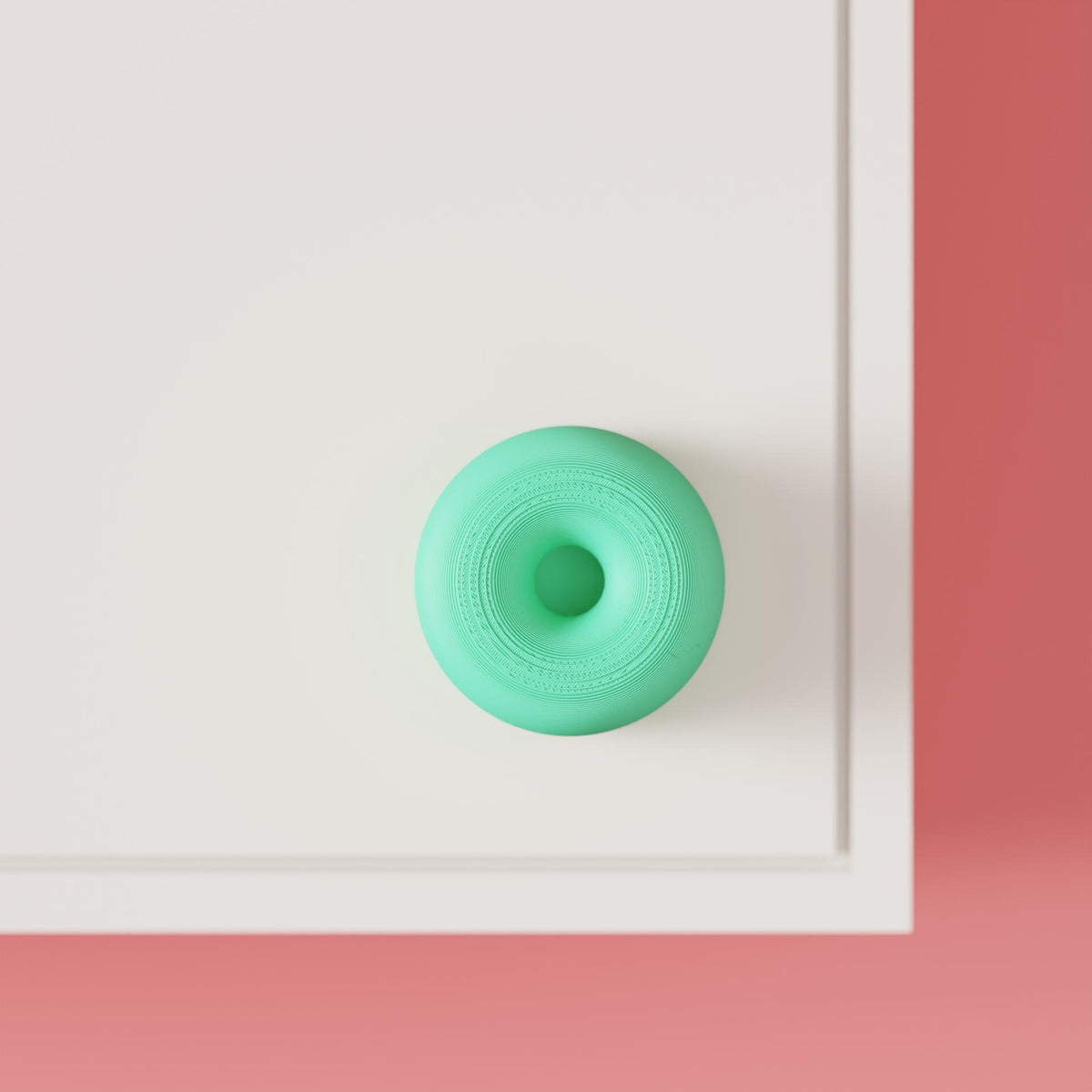Mint green round cabinet knob with concentric rings on a white cabinet, close front view.