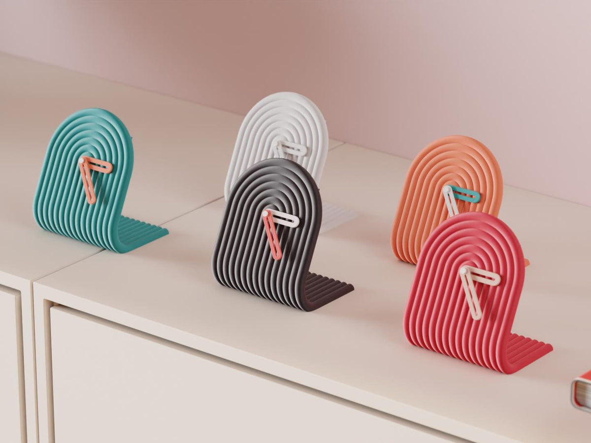 Archwave Sculptural Desk Clock examples in contrasting colors on a pale cabinet, showing the finished clock faces and hands.