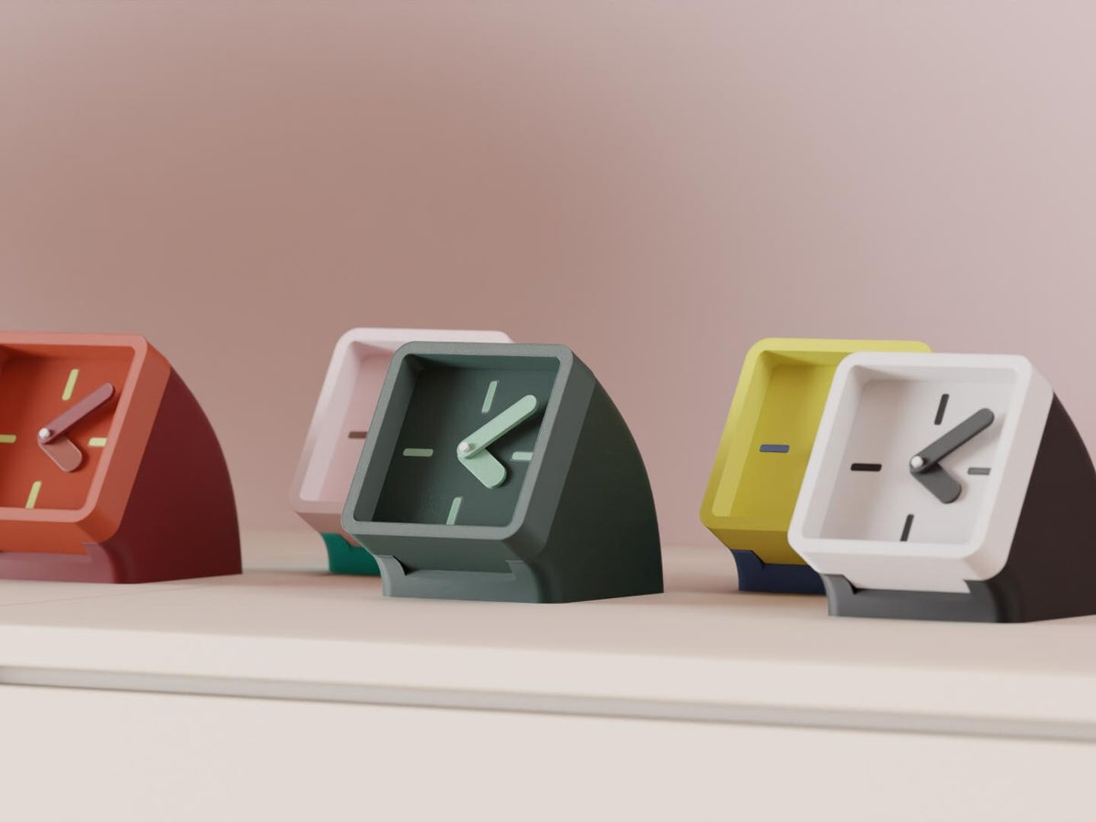 Framelean Desk Clock examples in contrasting colors on a pale cabinet, showing the finished clock faces and hands.